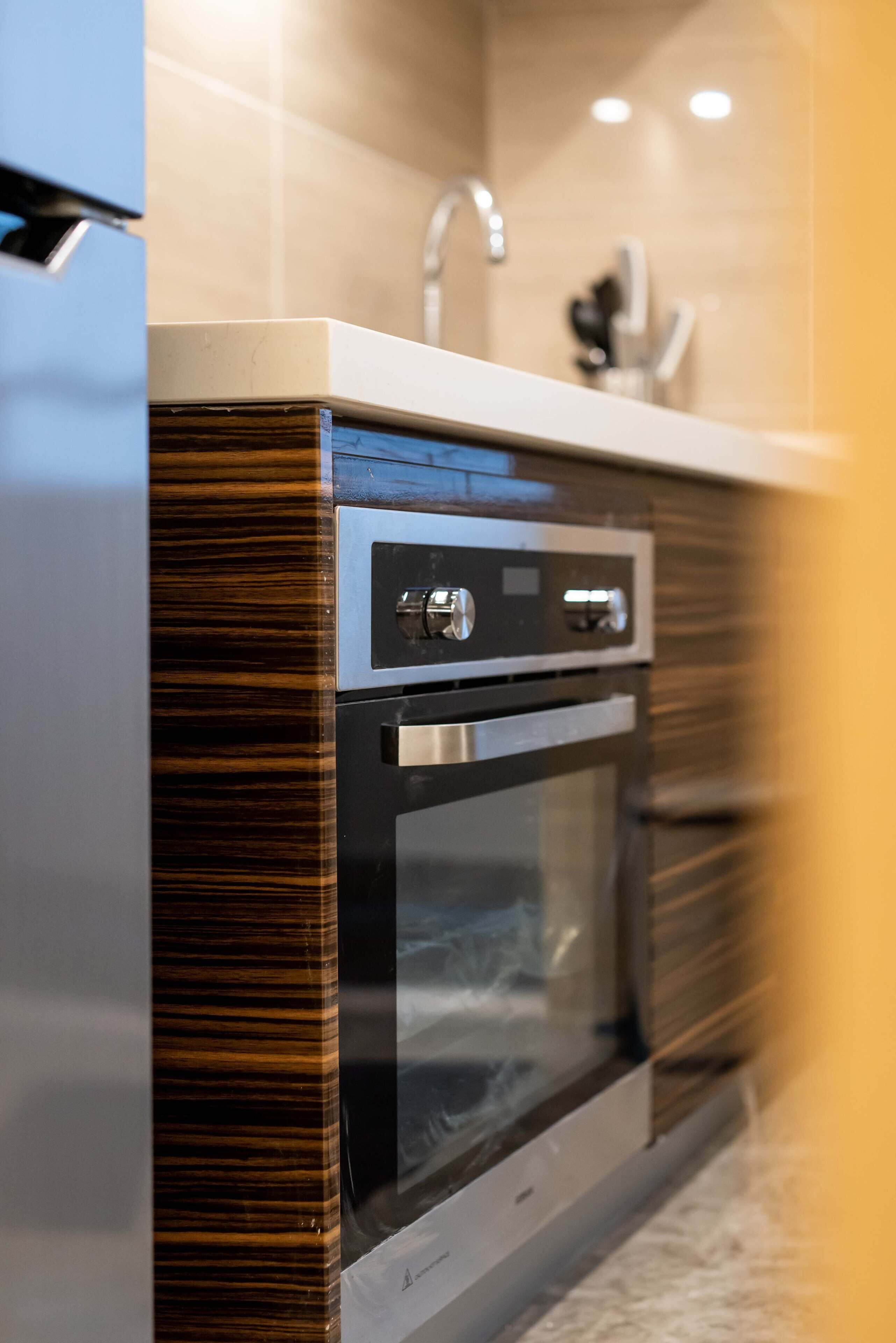 Een moderne keuken met een ingebouwde oven en magnetron, een roestvrijstalen kraan en een betegelde spatwand.