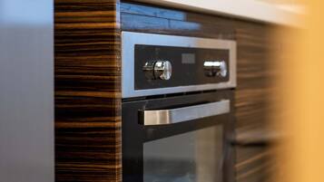 Een moderne keuken met een ingebouwde oven en magnetron, een roestvrijstalen kraan en een betegelde spatwand.