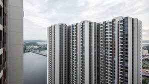 A high-rise building with multiple floors and balconies, overlooking a body of water and a bridge. - 2BR R&F Phase2, CIQ R&F Mall, Free Parking (Johor Bahru)