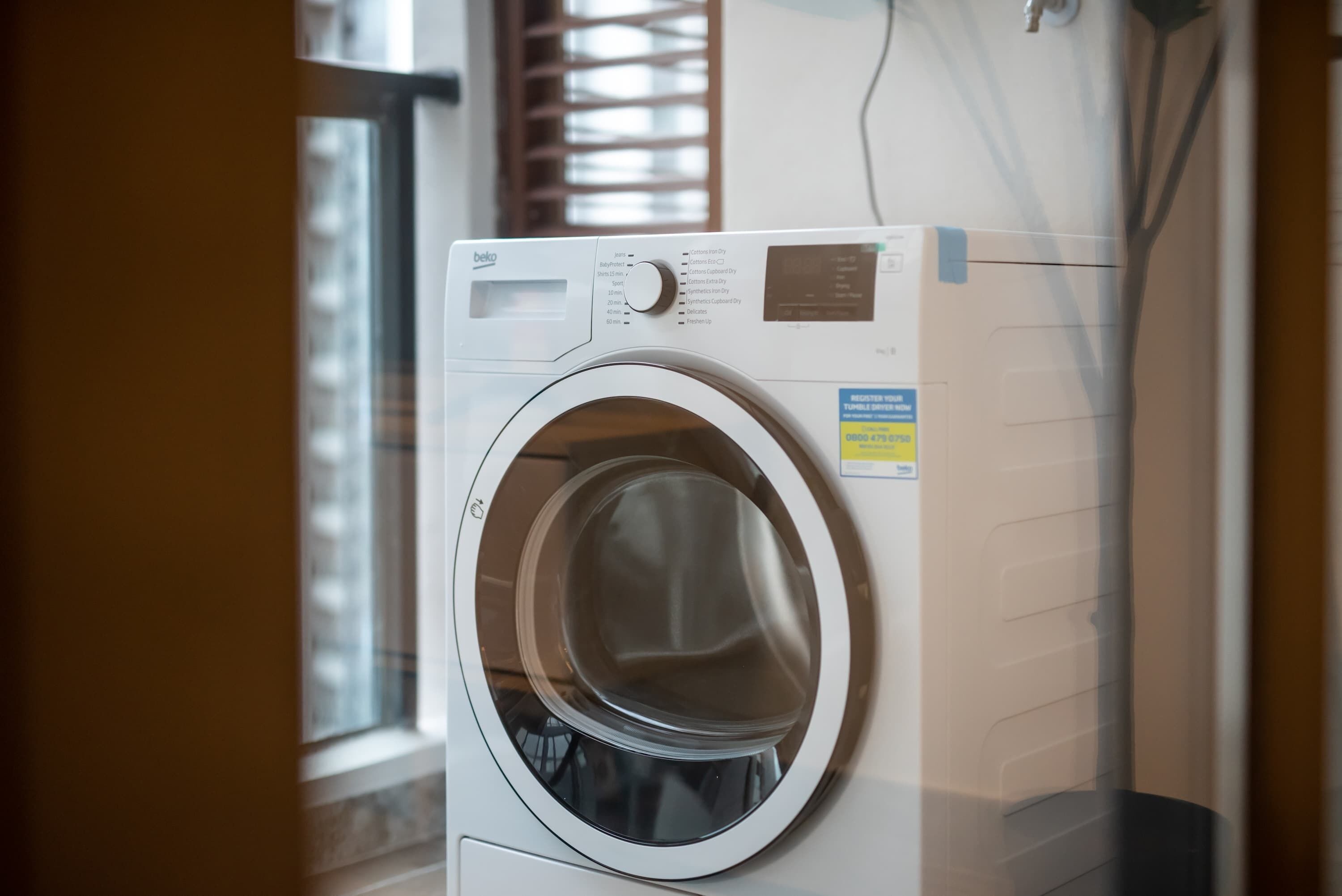 A front-loading washing machine with a control panel and a label on the door.