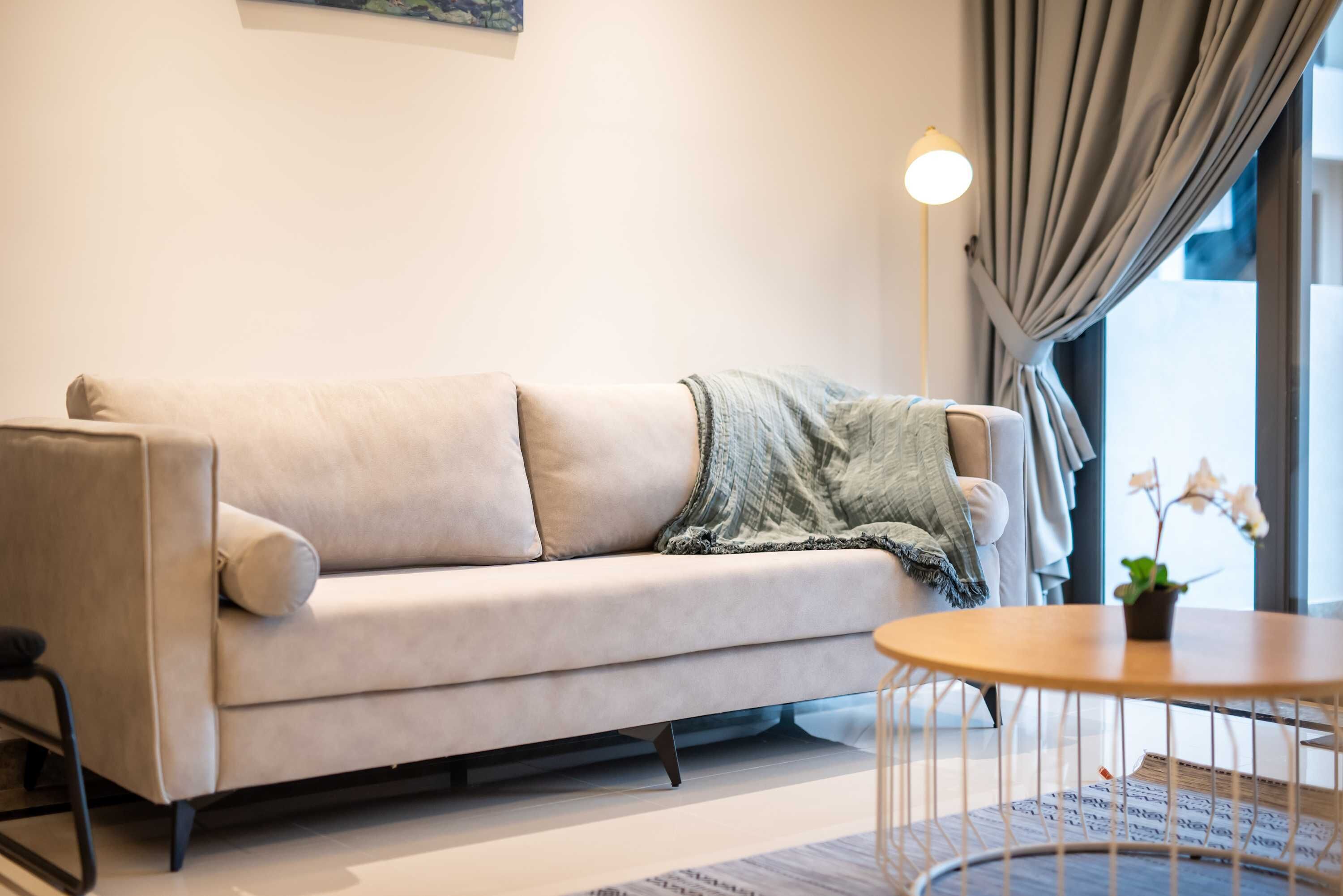 Un salon moderne avec un canapé, une petite table ronde et une lampe.