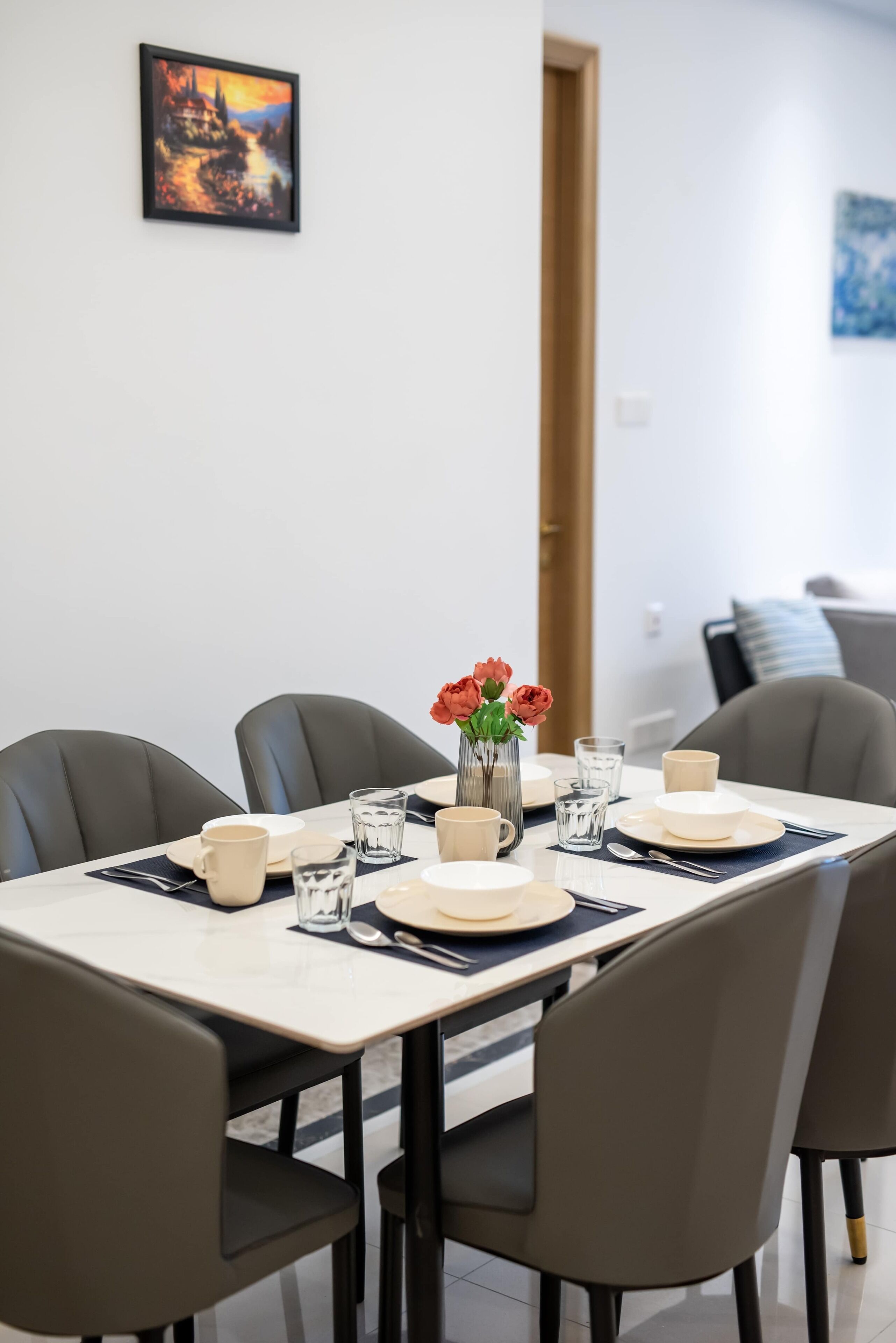 A dining table set with plates, cups, and a vase of flowers.