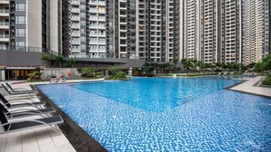 A swimming pool with lounge chairs, surrounded by high-rise residential buildings. - 2BR R&F Phase2, CIQ R&F Mall, Free Parking (Johor Bahru)