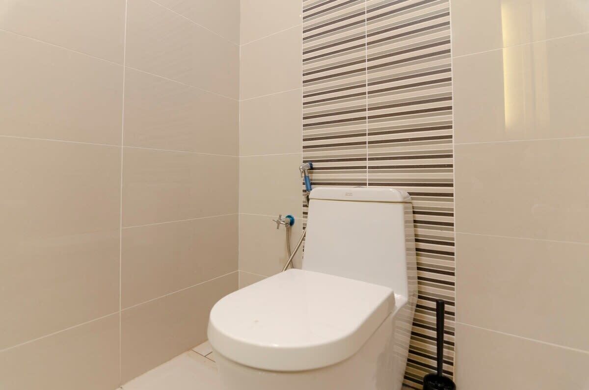 A small, modern bathroom with a toilet, a shower, and a striped wall.