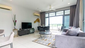 Un salón moderno con televisor de pantalla plana, sofá gris, mesa de comedor y un balcón con vistas.