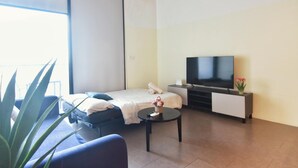A modern hotel room with a bed, a TV, a small table, and a potted plant. - Loft in Prime Bangsar Location (Kuala Lumpur)
