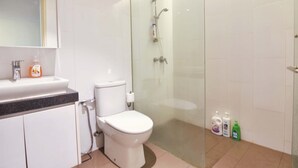 A modern bathroom with a toilet, sink, and glass-enclosed shower area. - Loft in Prime Bangsar Location (Kuala Lumpur)