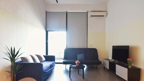 A modern living room with a sofa, a coffee table, a TV stand, and a potted plant. - Loft in Prime Bangsar Location (Kuala Lumpur)