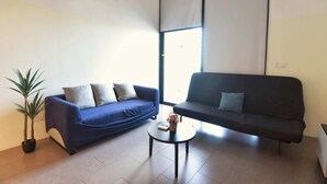 A living room with two sofas, a small table, and a potted plant. - Loft in Prime Bangsar Location (Kuala Lumpur)