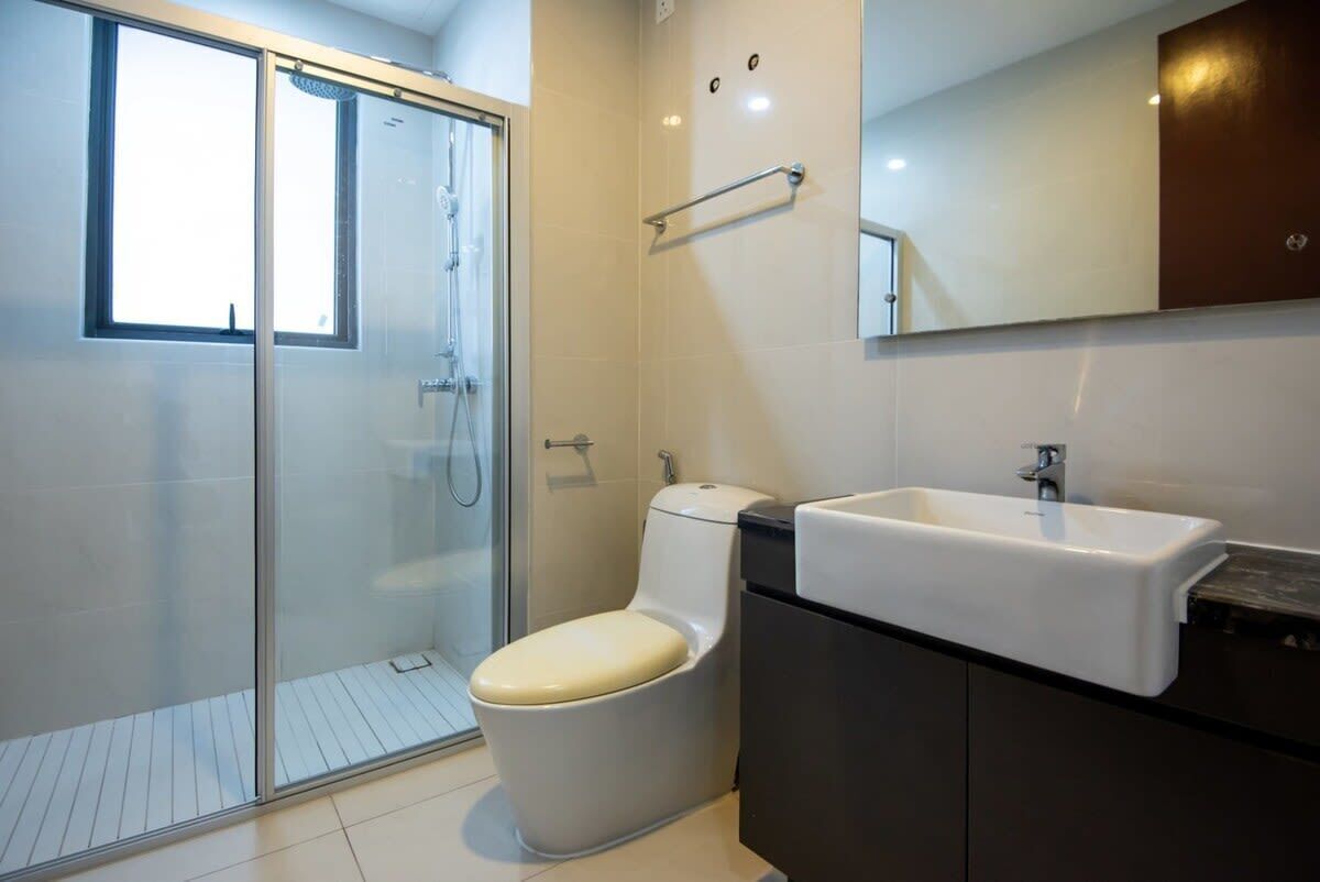 A modern bathroom with a glass shower enclosure, a toilet, and a sink.