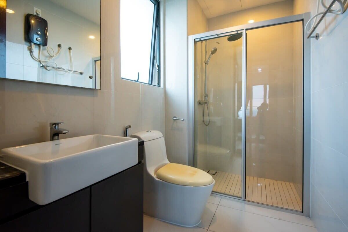 A modern bathroom with a large sink, toilet, and glass-enclosed shower.