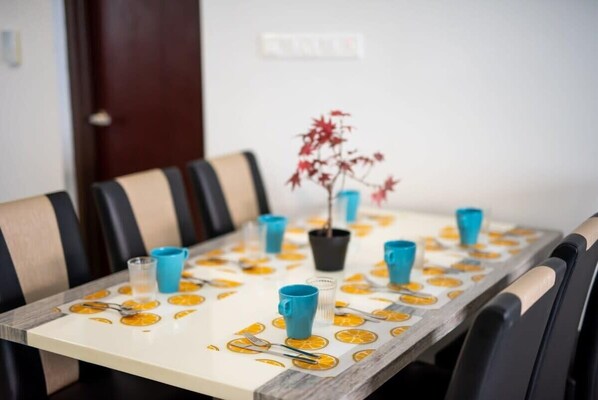 A dining table set with blue cups, orange slices, and a potted plant. - Chic 3BR in Danga Bay With Water Views & Parking (Johor Bahru)