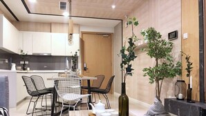 A modern kitchen with white cabinets, a dining area with a round table and chairs, and a living area with a sofa and a coffee table. - A Lux 2BR Suasana Suites in JB, Free Parking (Johor Bahru)