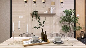 A dining table set with plates, bowls, glasses, and candles. There are hanging pendant lights above the table. - A Lux 2BR Suasana Suites in JB, Free Parking (Johor Bahru)