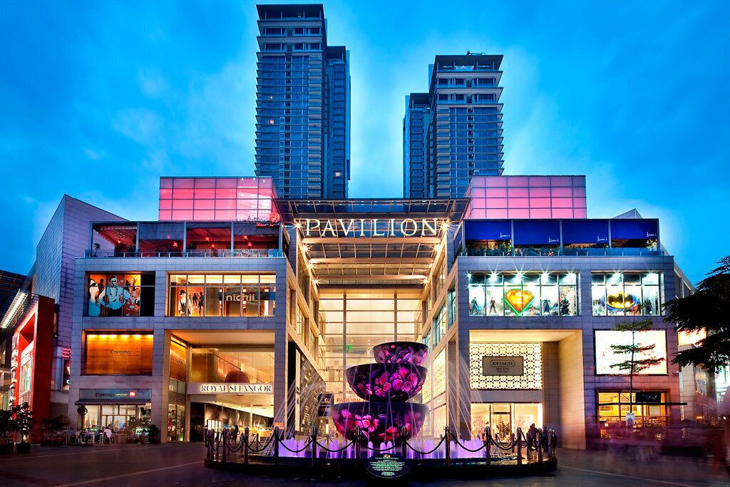 A multi-story building with a prominent sign reading 'PAVILION' and various retail stores on the ground floor.