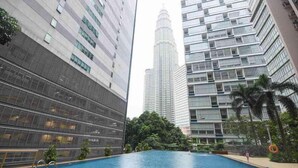 A modern building with a pool surrounded by high-rise buildings and greenery. - Central 2BR Apt 5 Mins Klcc Twin Towers, Bathtub (Kuala Lumpur)