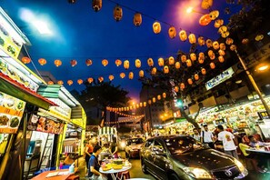 Un marché de rue animé, de nuit, avec des étals de nourriture et des lanternes.