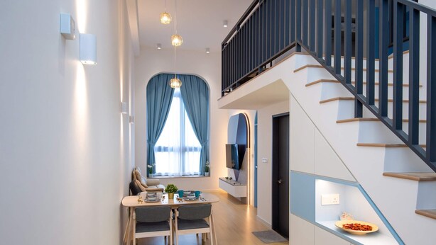 Un interior moderno con comedor, escalera y televisor montado en la pared.
