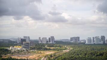 A cityscape with modern high-rise buildings and a dense green forest area.