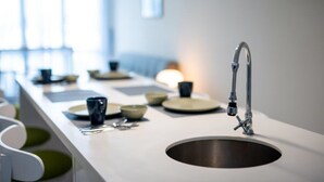 Een moderne keuken met een roestvrijstalen spoelbak, witte aanrechtbladen en een raam voor natuurlijk licht.