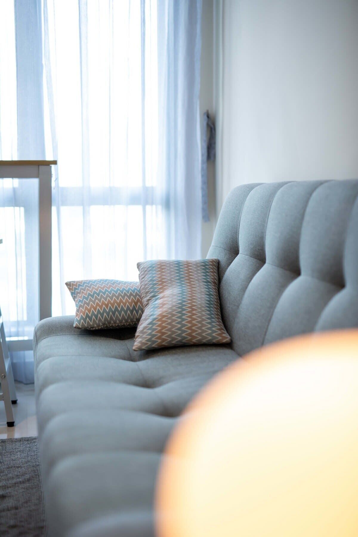 Un salón moderno con un sofá gris, dos cojines estampados y una mesita de madera.