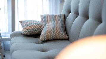 Un salón moderno con un sofá gris, dos cojines estampados y una mesita de madera.