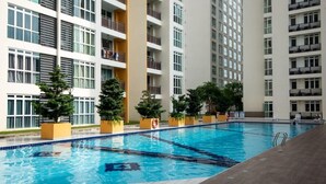 A swimming pool with clear blue water, surrounded by a modern building with balconies and windows. - Comfy 3BR Apt @ KSL Daya Near Ikea Tebrau, Parking (Johor Bahru)