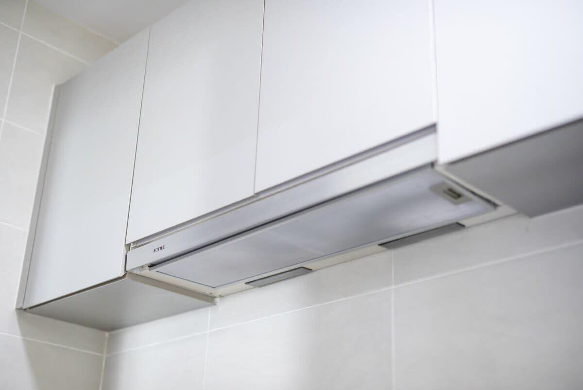 A kitchen with white cabinets and a stainless steel range hood.