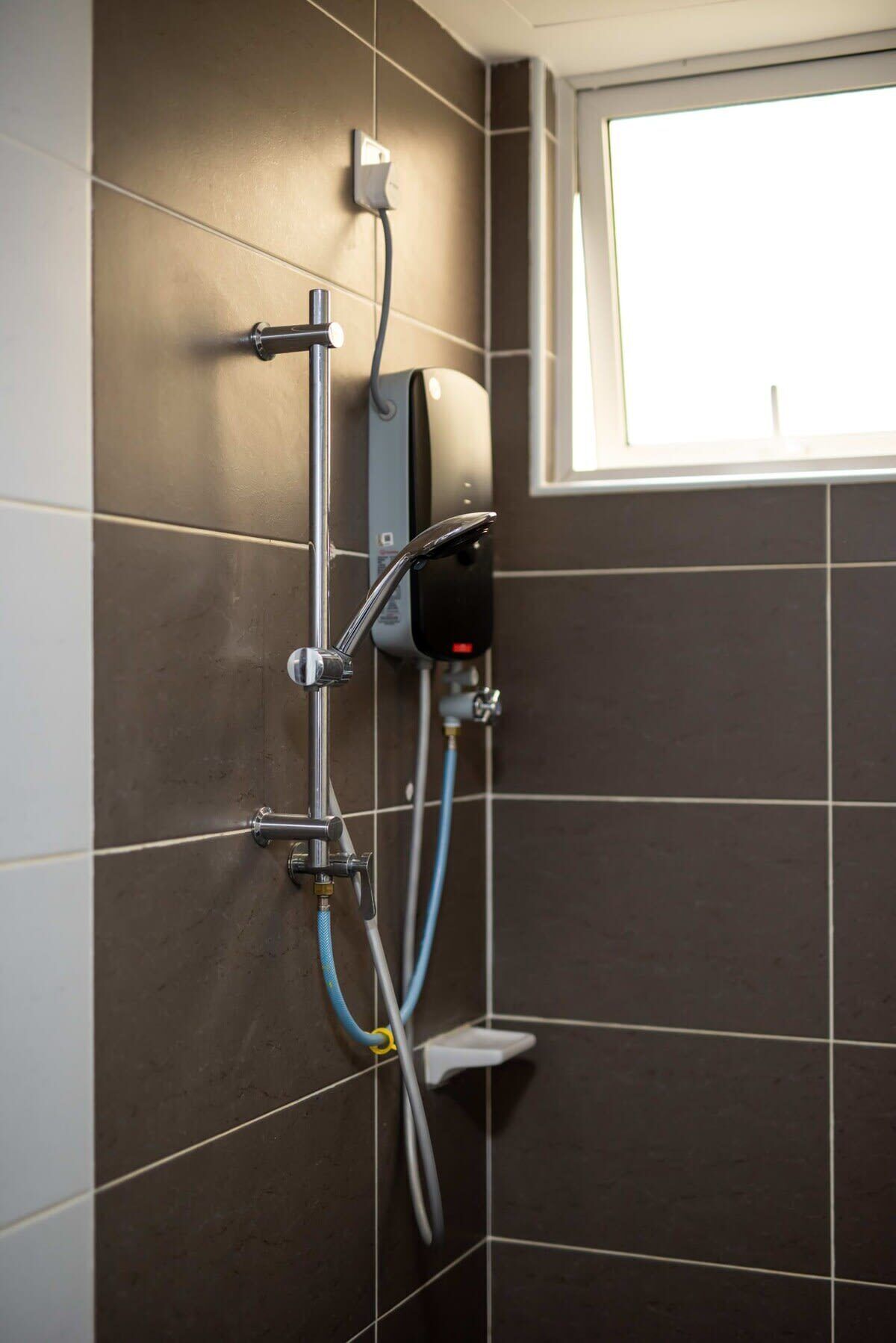 A shower with a handheld showerhead, a wall-mounted control panel, and a handheld shower attachment.