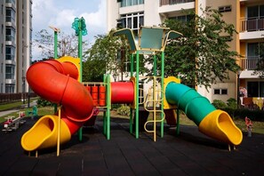 A playground with slides and climbing structures, surrounded by a residential building. - Comfy 3BR Apt @ KSL Daya Near Ikea Tebrau, Parking (Johor Bahru)