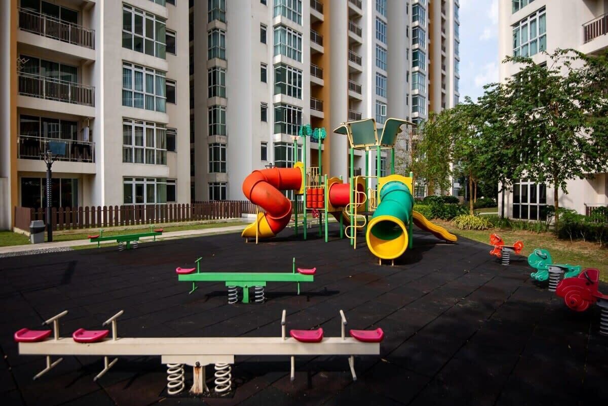 Un parque infantil con columpios, tobogán y estructura para escalar, rodeado de edificios de apartamentos.