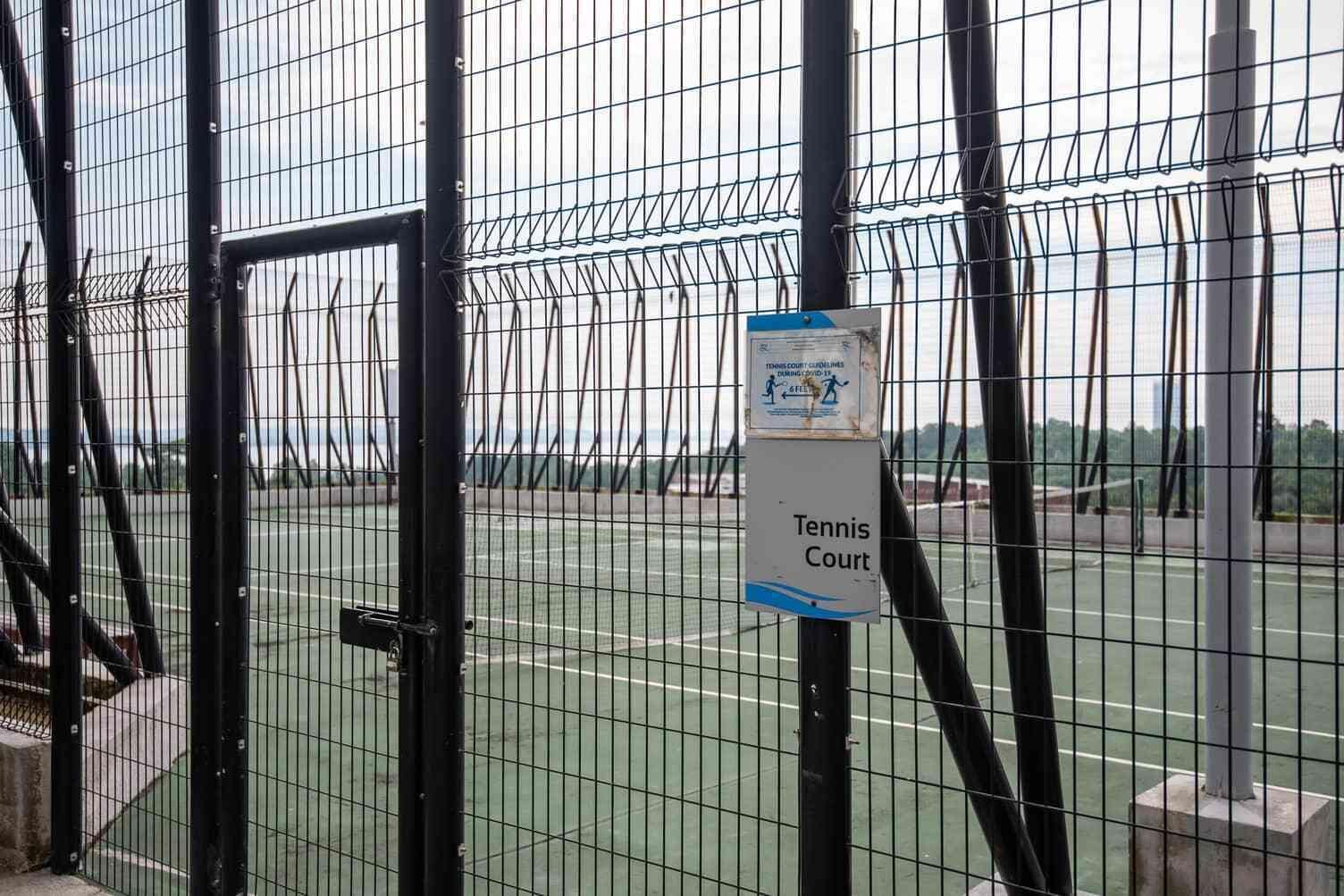A tennis court with a sign indicating it is a tennis court.