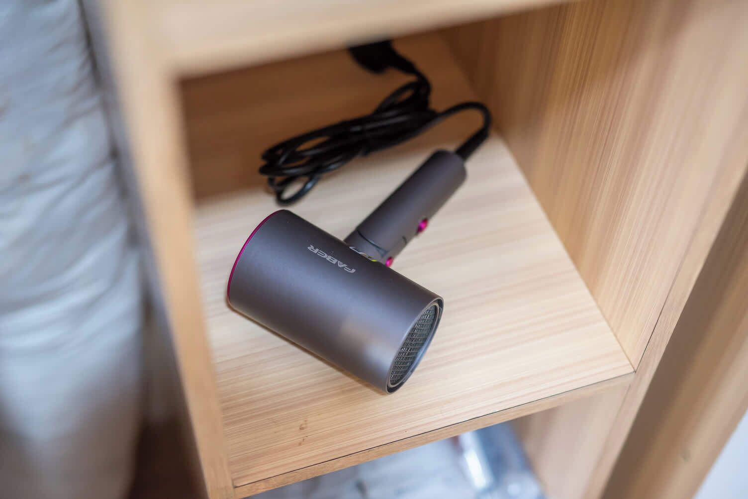 A wooden shelf with a cylindrical device and a coiled cable.