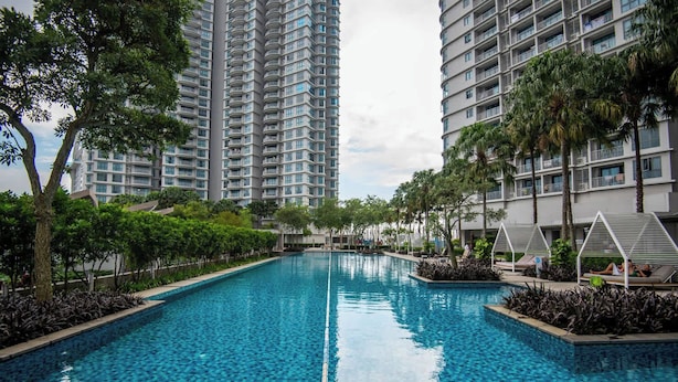 Una piscina rodeada de edificios residenciales altos, con sillas de descanso y vegetación.