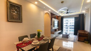 A dining area with a table set for four, a framed picture on the wall, and a view of the building outside. - 3BR Lsh33 KL Duke Highway Genting Free parking (Kuala Lumpur)