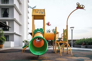 Un parque infantil con un tobogán, estructuras para escalar y una decoración con forma de mariposa.