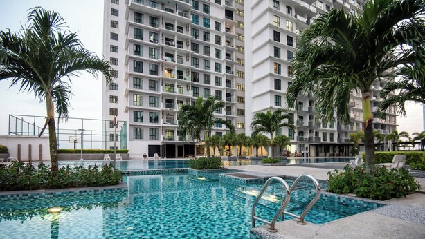 Un hôtel moderne doté d’une grande piscine extérieure entourée de palmiers et d’un immeuble à plusieurs étages en arrière-plan.