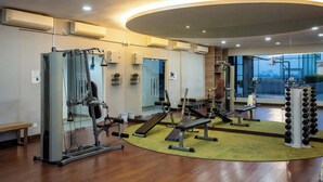 Une salle de sport moderne équipée de divers appareils d’exercice, d’un banc et d’un porte-haltères fixé au mur.