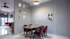 Un coin repas avec une table en bois dressée pour quatre personnes, entourée de chaises rouges. Un ventilateur de plafond et un luminaire suspendu sont visibles au-dessus de la table.
