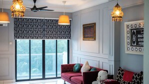 Un salon avec un canapé rouge, des coussins décoratifs, un ventilateur de plafond et des luminaires suspendus.