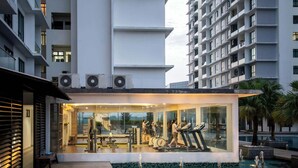 Une salle de sport moderne, dotée d’équipements d’exercice et d’une paroi en verre, entourée d’immeubles de grande hauteur.