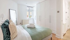 A bedroom with a bed, white wardrobe, and a window. - Lovely 1BR near Big Ben & Buckingham Palace (London)