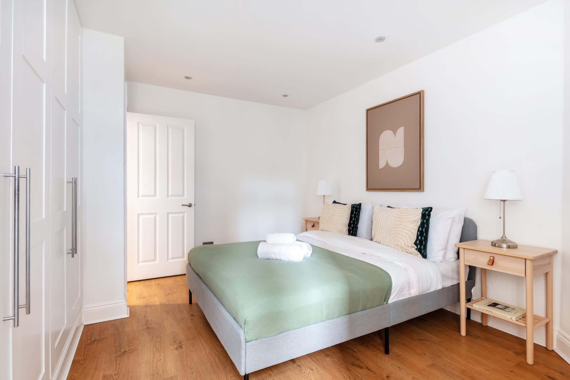 A neatly arranged bedroom with a bed, bedside tables, and a door.