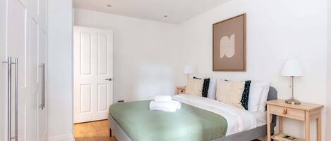 A neatly arranged bedroom with a bed, bedside tables, and a door.