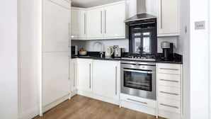 A modern kitchen with white cabinets, stainless steel appliances, and a black countertop. - Lovely 1BR near Big Ben & Buckingham Palace (London)
