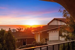 A residential house with a garage, a small porch, and a view of the sunset over the ocean.