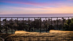 A balcony with a view of a park and the ocean.