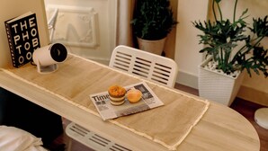 Ein Tisch mit einer Zeitung, einem Muffin und einer Kaffeemaschine.