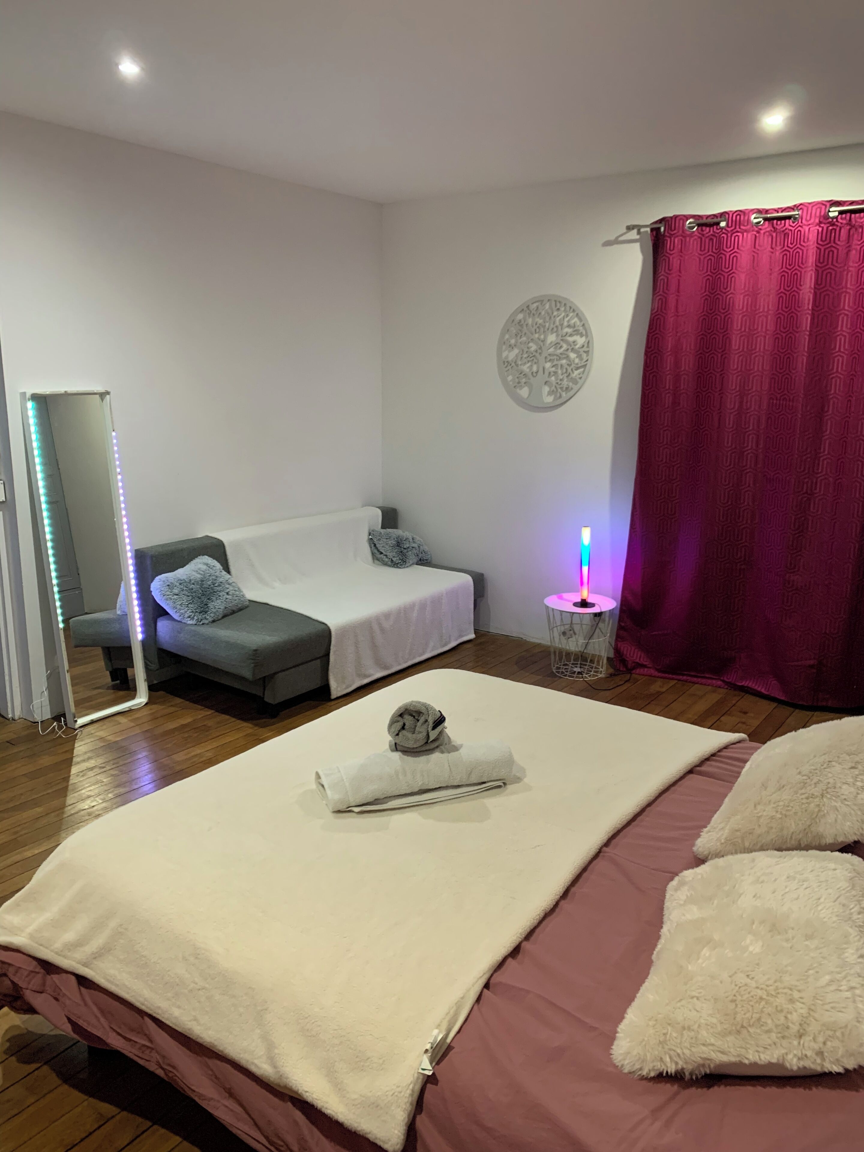 Un dormitorio con cama, mesita de noche, espejo y un adorno en la pared.