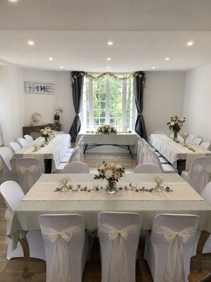 A conference room with a long table, white chairs, and floral centerpieces.